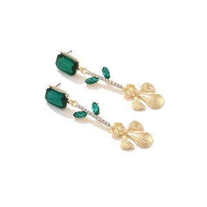 Détail de boucles d'oreilles pendantes émeraude avec pétales dorés et cristaux