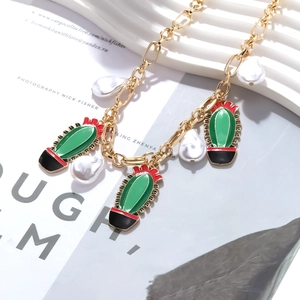 Detail of gold chain necklace with colorful enamel cactus charms and baroque pearls