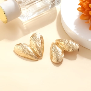 Retro gold metallic open shell earrings with natural texture on a warm minimalist background