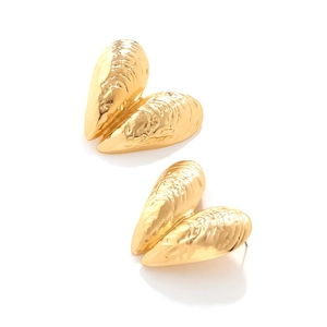 Close-up of golden shell earrings with unique hammered texture and vintage beach style