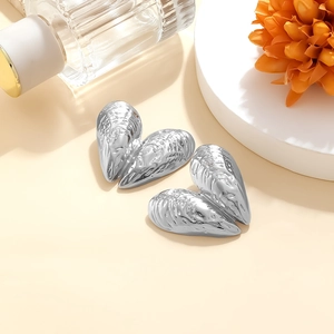 Macro detail of silver mussel shell earrings with high-polish metallic texture and texture