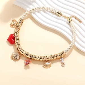 Détail du collier de perles d'été avec breloques crabe et hippocampe dorés sur corde tressée