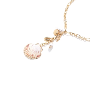 Détail d'un collier doré avec coquillage rose naturel et breloques en forme d'arêtes
