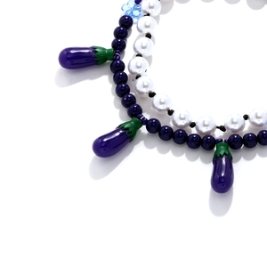Faux pearl necklace with blue beads and cute purple eggplant pendant on white background
