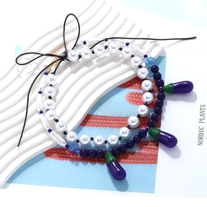 Faux pearl necklace with purple eggplant pendant and black bow for summer styling