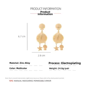 Détail de boucles d'oreilles coquillage dorées, pendentifs étoile de mer et poisson