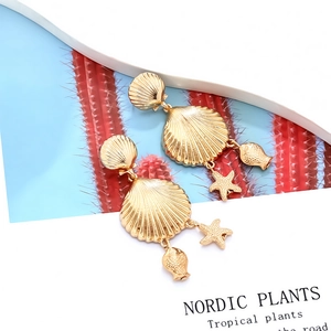 Boucles d'oreilles dorées style océan avec pendentifs coquillage, étoile de mer et poisson