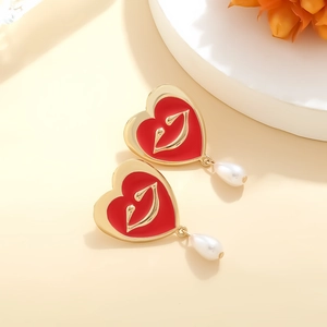 Retro gold earrings featuring red enamel hearts with lip detail and teardrop faux pearls