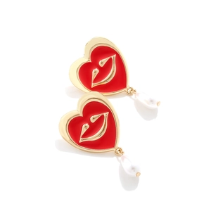 Macro shot of red heart base with golden lips and white baroque pearl drop earrings