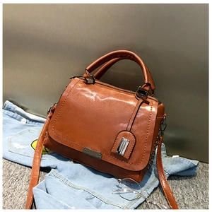 Gros plan d'un sac à main marron brillant en similicuir avec plaque en métal sur denim