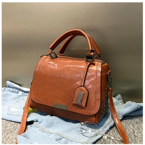 Gros plan du sac à main marron caramel avec clous métalliques et détails vintage