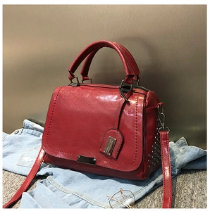 Vue détaillée du sac à main rouge brillant en similicuir avec rivets sur denim