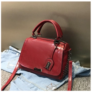 Détail du sac en cuir brillant rouge avec rivets punk et boucles vintage en bronze