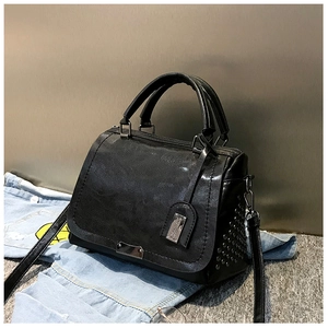 Détail d'un sac à main noir en similicuir avec rivets argentés et plaque en métal
