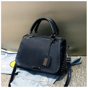 Détail d'un sac Boston bleu foncé avec rivets métalliques et bandoulière sur jean