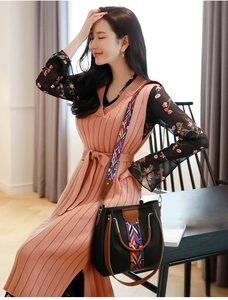Detail of black faux leather handbag featuring colorful ethnic woven strap and brown handles