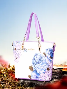 Detail of floral tote bag with blue patterns, purple leather trim, and gold chain handles