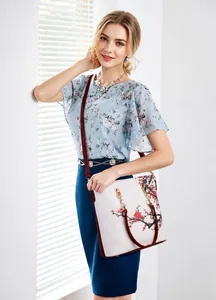 Fashionable white handbag with red plum pattern carried by a model on shoulder