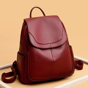 Detail of burgundy pebbled leather backpack showing flap closure and embossed brand logo