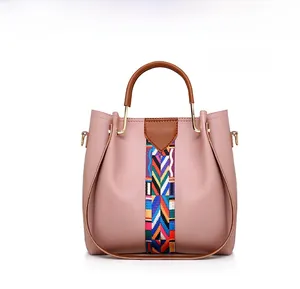 Detail of pink tote bag featuring a colorful woven strap and gold metal hardware accents