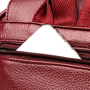 Macro view of burgundy pebble leather backpack showing zipper pocket and phone storage