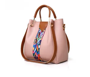 Side view of elegant nude pink handbag with brown leather trim and colorful woven strap detail