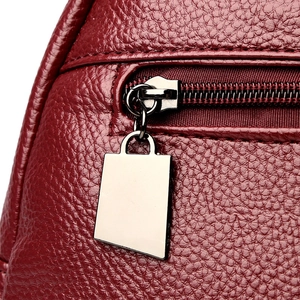 Detail of wine red pebble leather texture with silver zipper and handbag charm