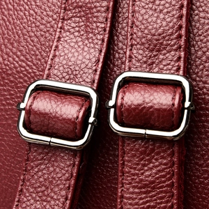 Macro detail of dark red pebbled leather bag with silver metal adjustable buckles