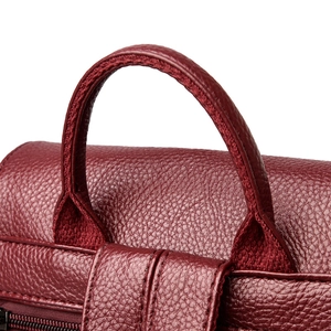 Detailed close-up of wine red lychee grain leather stitching and handle on a backpack