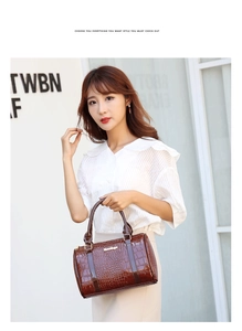 Detail of dark brown faux crocodile leather handbag with glossy finish and double handles