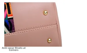 Detail of pink faux leather bag showing gold anti-wear studs and colorful woven strap