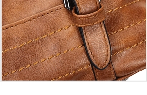 Detail van bruine leren tas met getextureerd oppervlak en geaccentueerd met gele naden