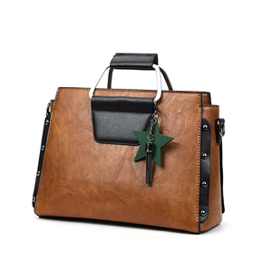 Détail du sac cabas vintage montrant la texture du cuir ciré et les rivets latéraux