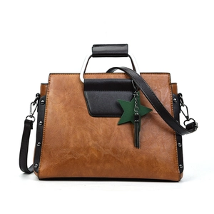 Détail du sac à main en cuir marron caramel avec breloque étoile et poignée en métal