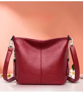 Detail of burgundy lychee leather bucket bag with silver metal hooks and tassel charms