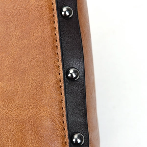 Détail macro du sac en cuir marron avec rivets argentés et coutures soignées