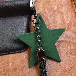 Gros plan du cuir noir et marron avec un pendentif étoile verte sur un sac cabas