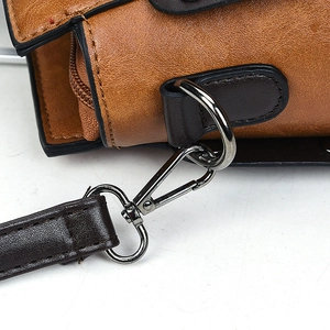 Vue détaillée du fermoir mousqueton en métal gris foncé sur un sac à main en cuir marron