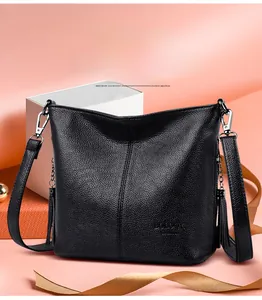 Detail of black lychee grain leather bucket bag with tassel and logo on pink background