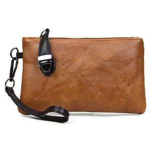 Détail de la pochette en cuir grainé marron foncé avec fermeture éclair et dragonne