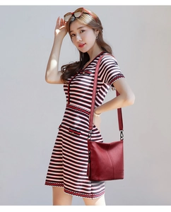 Detail of red tassel bucket bag in lychee pattern leather worn by model with stripe dress