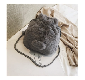 Detail of plush grey faux fur bucket bag featuring a cute furry tail and drawstring
