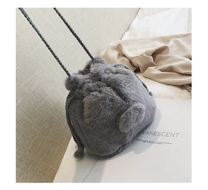 Detail of grey faux fur drawstring bucket bag with soft texture and spherical charm