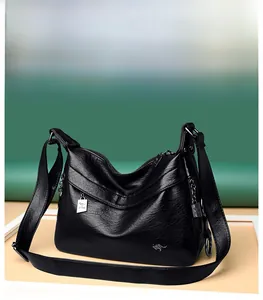 Detail of black soft leather hobo bag featuring kangaroo logo and adjustable strap