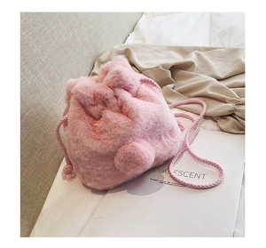 Detail of pink faux fur bucket bag featuring fluffy texture and braided drawstring strap
