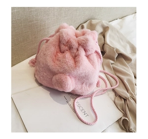 Close-up of soft pink faux fur drawstring bucket bag with cute plush pom-pom detail