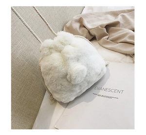Detail of white faux fur bucket bag with drawstring closure and soft plush texture