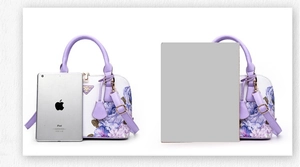 Detail view of printed shell bag featuring lavender handles and floral rose pattern