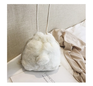 Detail of white plush faux fur drawstring bucket bag with thick woven shoulder strap