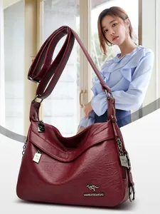 Detail of burgundy lychee leather crossbody bag with kangaroo logo and adjustable strap
